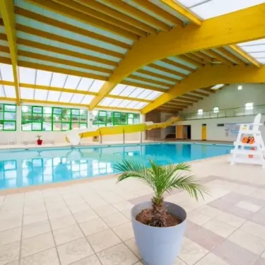 Camping Moncalm - piscine intérieure avec toboggan et plante en pot