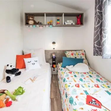 Chambre d'enfant avec lits jumeaux et jouets dans Mobil Home Bahia Confort, Camping La Touesse