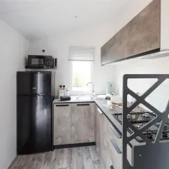Cuisine équipée d'un réfrigérateur, micro-ondes et plaque de cuisson dans Mobil Home Bahia Confort, Camping La Touesse