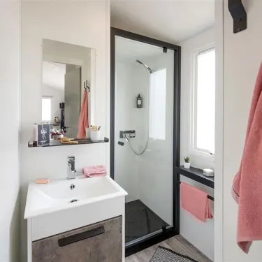 Salle de bain avec douche, lavabo et miroir dans Mobil Home Bahia Confort, Camping La Touesse
