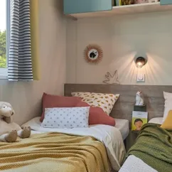 Chambre double avec couvre-lit jaune et oreiller rouge dans Mobil Home Bahia Modulo Confort