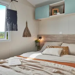 Lit double avec couvre-lit beige et décorations suspendues dans Mobil Home Bahia Modulo Confort