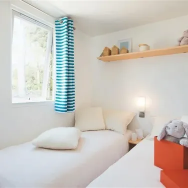 Chambre du Mobil Home Bora Bora, Camping La Touesse, lit, rideaux bleus, étagère