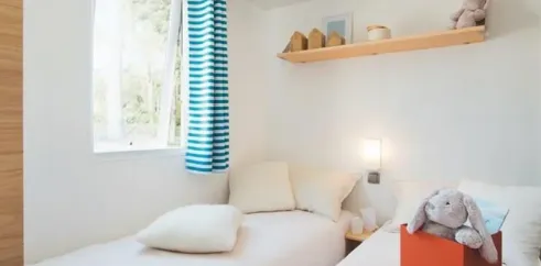 Chambre du Mobil Home Bora Bora, Camping La Touesse, lit, rideaux bleus, étagère