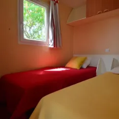 Mobil Home Flores 2 Chambres 4 Personnes- Camping La Touesse : deux lits, fenêtre, rangements