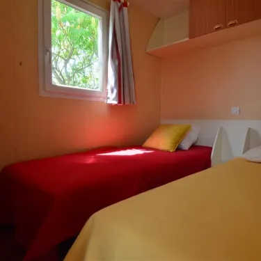 Mobil Home Flores 2 Chambres 4 Personnes- Camping La Touesse : deux lits, fenêtre, rangements