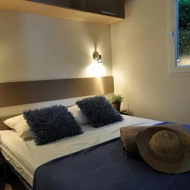 Lit double avec coussins et chapeau dans le Mobil Home Maldives à Camping La Touesse