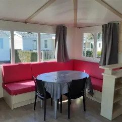 Salle à manger avec canapé rouge et table ronde dans le Mobil Home Maldives