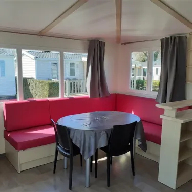 Salle à manger avec canapé rouge et table ronde dans le Mobil Home Maldives