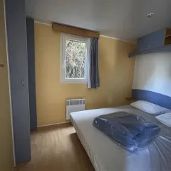 Mobil Home Ophéa 2 Chambres 4 Personnes - Camping La Touesse : chambre avec lit et radiateur