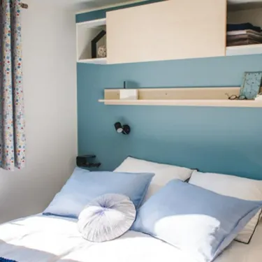 Chambre Mobil Home Smala 4 Chambres 8 Personnes- Camping La Touesse avec lit et étagères murales