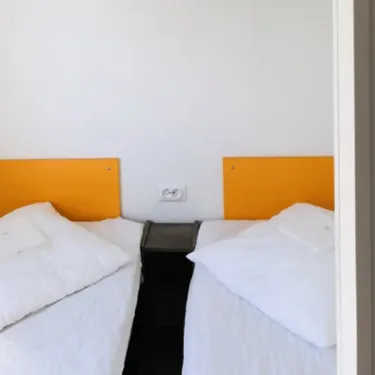 Mobil Home Premium 2 Chambres 4 Personnes 28m² - Camping Paradis de Rhuys : deux lits simples avec tête de lit orange