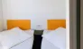 Mobil Home Premium 2 Chambres 4 Personnes 28m² - Camping Paradis de Rhuys : deux lits simples avec tête de lit orange