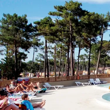 Camping Atlantique Club Montalivet - personnes profitant d'une piscine entourée de pins