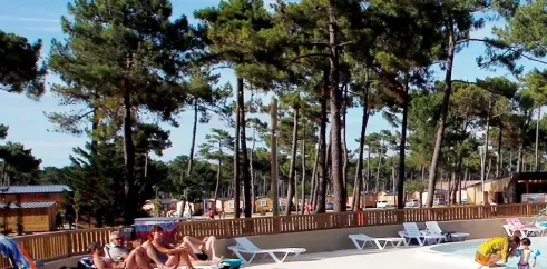 Camping Atlantique Club Montalivet - personnes profitant d'une piscine entourée de pins