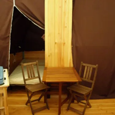 Tipi Confort 2 Chambres 4 Personnes - Camping Paradis de Rhuys : intérieur avec table et chaises en bois