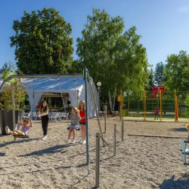 Camping Le Ried - enfants et adultes sur un terrain de sable avec cabane blanche
