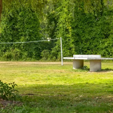 Photo Camping Les Fontaines : banc et filet de volleyball en plein air