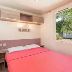 Mobil Home Comfort 3 Chambres 6 Personnes - Camping Ty Nadan : chambre avec lit double et murs en bois