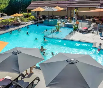 Piscine extérieure avec baigneurs et parasols au Camping Paradis L'Arada Parc