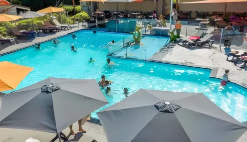 Piscine extérieure avec baigneurs et parasols au Camping Paradis L'Arada Parc