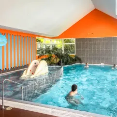 Piscine intérieure avec toboggan et baigneurs au Camping Paradis L'Arada Parc