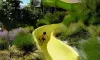 Enfant glissant sur un toboggan jaune au Camping Paradis L'Arada Parc