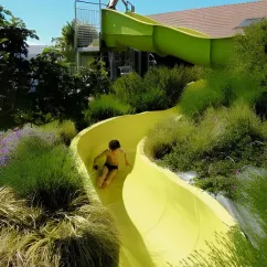 Enfant glissant sur un toboggan jaune au Camping Paradis L'Arada Parc