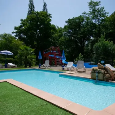 Piscine avec toboggan et chaises longues au Camping des Bains