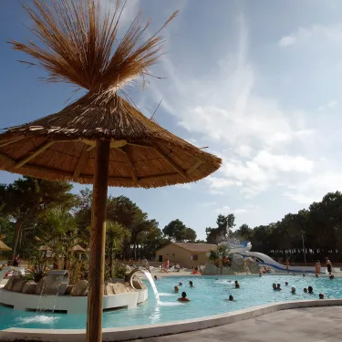 Ombrelle en paille au bord d'une piscine dans le camping Atlantique Club Montalivet