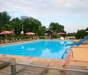 Piscine avec toboggan et chaises longues au Camping Fontaine du Roc