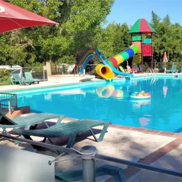 Piscine avec toboggan coloré et chaises longues au Camping Fontaine du Roc