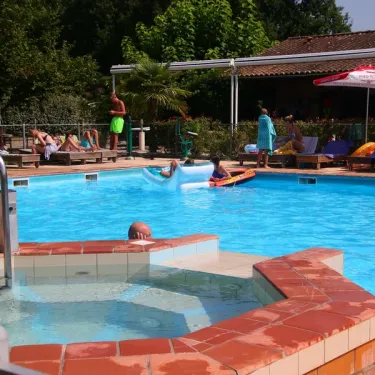 Piscine avec personnes nageant et chaises longues au Camping Fontaine du Roc