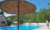 Piscine du Camping Au Soleil d'Oc sous un grand parasol de paille