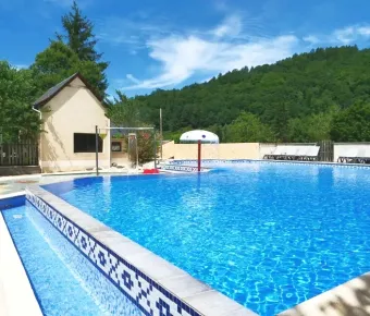 Piscine du Camping Au Soleil d'Oc entourée de verdure et de mobil-homes.