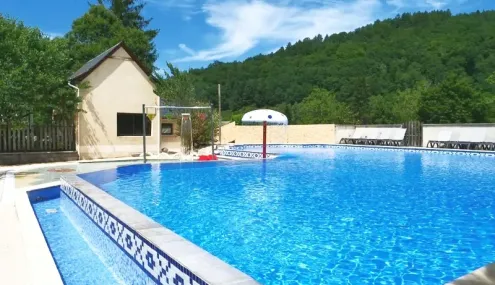 Piscine du Camping Au Soleil d'Oc entourée de verdure et de mobil-homes.