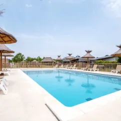 Piscine avec chaises longues et parasols au Camping Le Plan d'eau