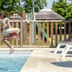 Enfant sautant dans la piscine au Camping Le Plan d'eau