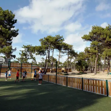 Enfants jouent sur terrain de sport en herbe au Camping Atlantique Club Montalivet