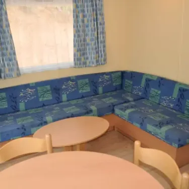 Cottage 2 Chambres 4 Personnes - Camping des Bastides : canapé en L et tables