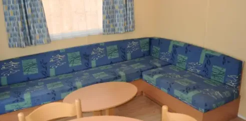 Cottage 2 Chambres 4 Personnes - Camping des Bastides : canapé en L et tables