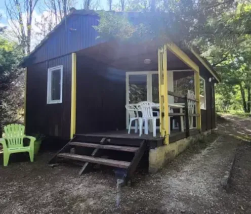 Chalet 2 Chambres 4 Personnes - Camping des Bastides : cabane en bois avec véranda et chaises