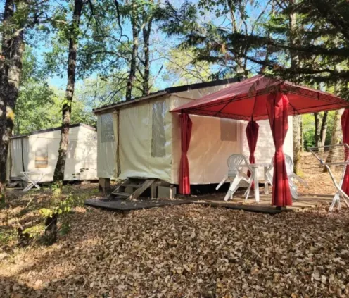 Tente avec table et chaises sous une tente rouge à Camping des Bastides