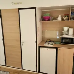 Tithome 2 Chambres 4 Personnes Sans Sanitaires - Camping des Bastides : cuisine compacte avec réfrigérateur, four à gaz et micro-ondes.