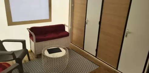 Tithome 2 Chambres 4 Personnes Sans Sanitaires - Camping des Bastides : salon avec canapé, table ronde et tapis en tissu.
