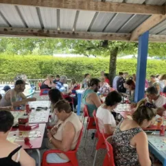 Camping les Naïades : groupe de personnes autour de tables en plein air
