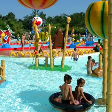 Enfants jouant dans une piscine avec des structures en bambou et un ballon de clown, Camping La Rive