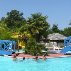 Piscine avec pont bleu et palmiers au Camping Lou Puntaou