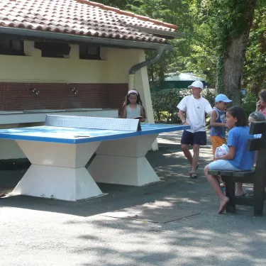 Camping Lou Puntaou : enfants jouent au ping-pong en extérieur.