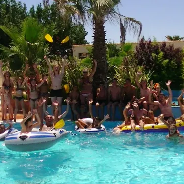 Camping La Plage et le Bord de Mer : groupe souriant sur des flotteurs dans la piscine.